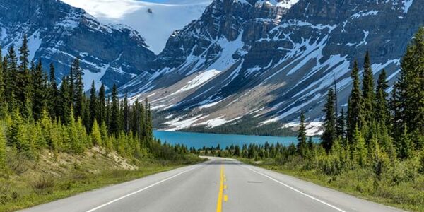 Scenic highway leading to snow-capped mountains near Banff, showcasing the breathtaking landscapes of the Rocky Mountain range in Western Canada. Perfect for Western Canada Rockies Adventure Tours.