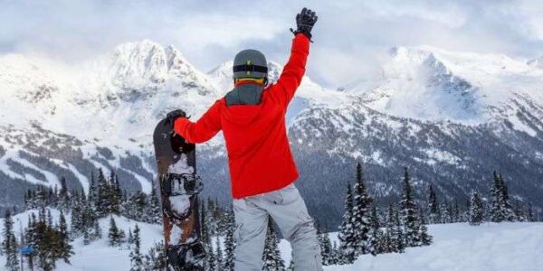 Snowboarder carving through fresh powder with Canadian Rocky Mountains backdrop